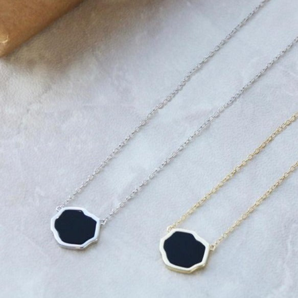 Sterling silver and 14k black onyx single stone necklace on marble background