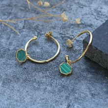 Load image into Gallery viewer, Pair of 14k gold 1&quot; hoop earrings with green malachite charms leaning against black stone on stone background

